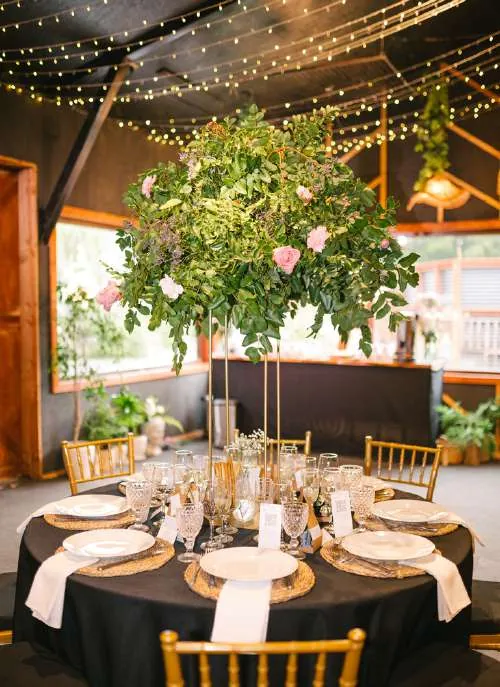 Mesa de invitados con arreglo floral en pedestal alto