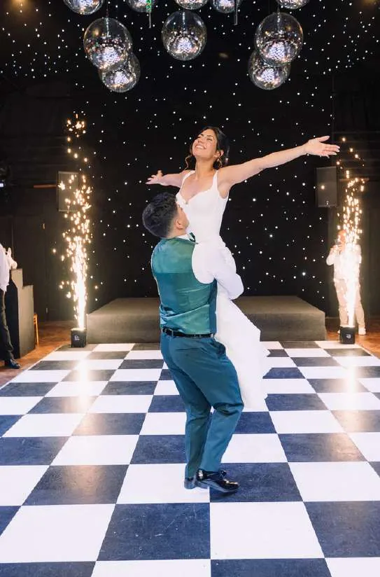 Novios bailando en la pista ajedrez con pirotecnia fría